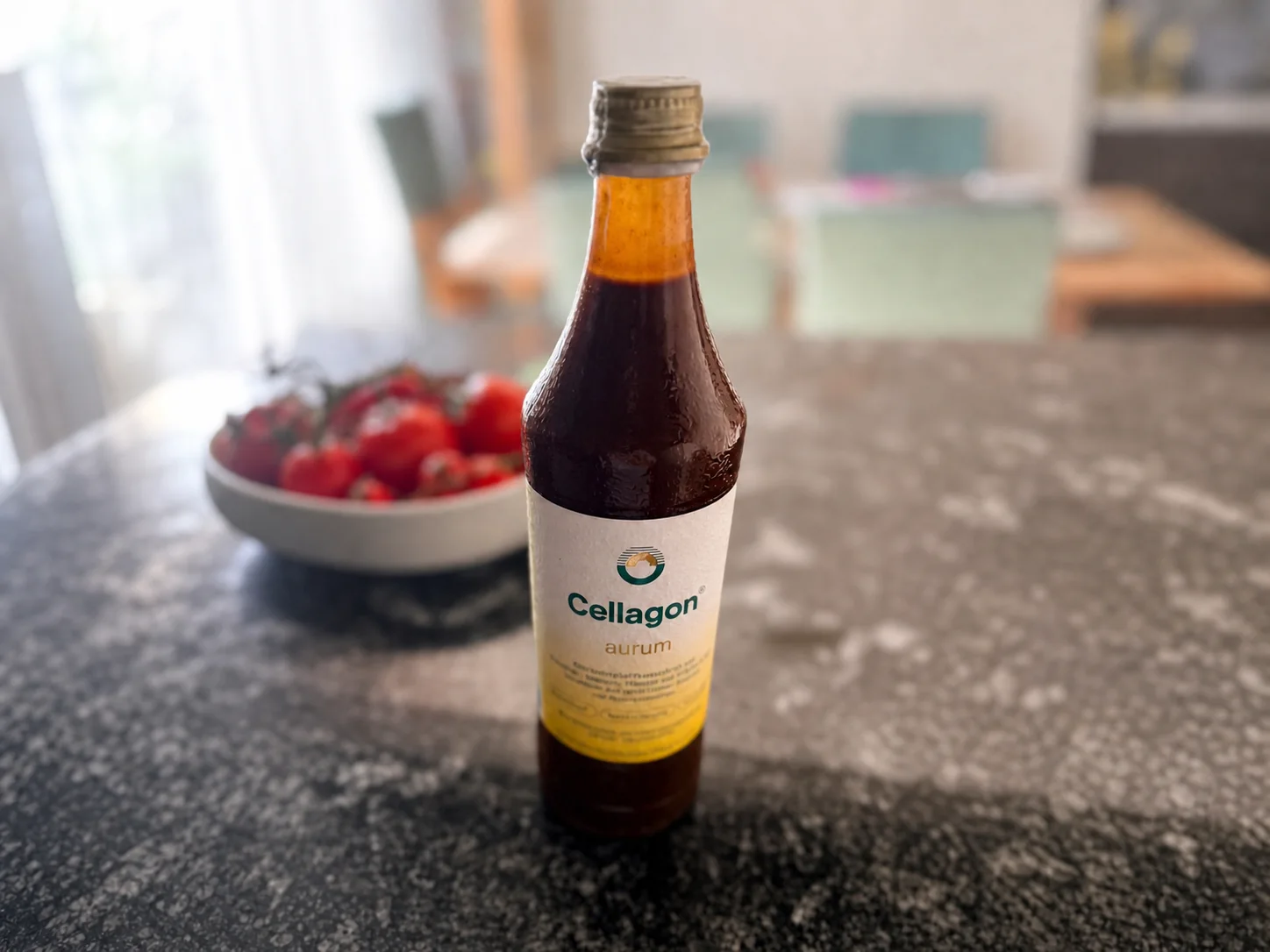 Flasche Cellagon aurum auf Yvonnes dunkler Granitarbeitsfläche, im Hintergrund eine Schale mit Tomaten